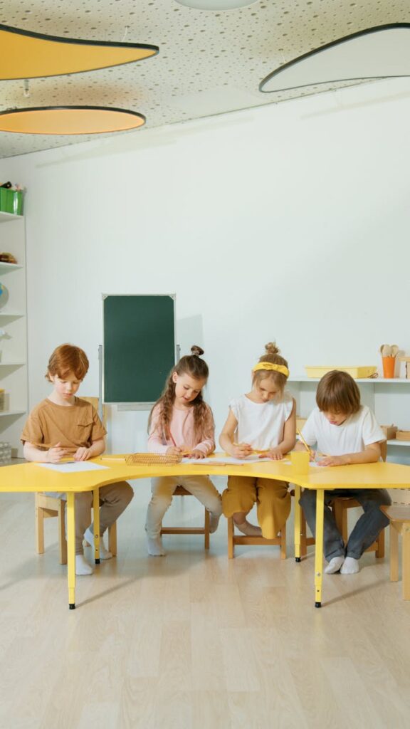 Children learning together at a table in a bright classroom setting.